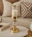 Gold candle holder with a candle on a marble surface in a living room setting.