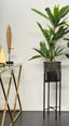 Artificial tropical plant with lush green leaves in a decorative black metal stand, styled in a modern interior.