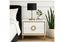 White Balmain bedside table with gold trim styled beside bed with lamp, book, and indoor plant.