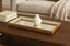 Decorative mirror gold tray with a white vase on a wooden table in a living room setting.
