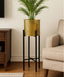 Gold metal plant stand with a green plant in a living room setting.