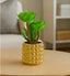 Small gold potted plant in a decorative gold pot on a table with a blurred background