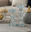 Two decorative glass candle holders on a surface with a blurred background