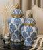 Decorative blue and white jars with gold lids on a table.