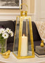 Gold lantern with a lit candle on a table in a living room setting.