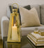 Gold lantern with a lit candle on a reflective surface in a living room setting.