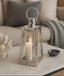 Silver lantern with a lit candle on a marble surface in a living room setting.