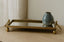 Antique gold mirror tray with a blue vase on a wooden surface