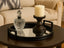Decorative mirror round black tray with a crystal decanter and candle on a table in a living room setting.
