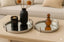 Decorative mirror tray set on a coffee table including a candle, vase, and mirror trays.