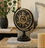 Decorative Black Gear Mechanical table clock on a table with a plant and books in the background