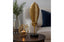 Decorative antique gold leaf sculpture and geometric candle holder on a table with a blurred background