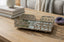 Decorative metal rectangle tray on a wooden surface with books and a crystal in the background