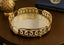Decorative gold round mirror trayl on a wooden surface with 'Yves Saint Laurent' book in the background.