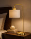 Gold with white table lamp on a nightstand with a soft glow in a bedroom setting