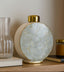 Decorative jar with gold base and white textured shade on a shelf.