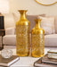 Two gold decorative vases on a table with a living room background