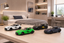 Four miniature sports car model toys arranged on a light wood table in a modern bedroom setting.