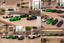 A collage of six photos showing several toy sports car models in different colors, including white, green, black, and dark blue, arranged on a wooden table and shelf in a modern living room setting.