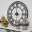 Black plain metal wall clock styled above console with gold and silver jars.
