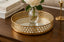 Gold decorative mirror tray with a vase of flowers on a wooden surface