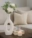 White vase with flowers on a coffee table in a living room setting