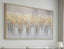 Abstract painting with gold and gray tones on a wall above a sofa.