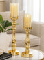 Two gold candle holders with candles on a table in a living room setting.