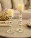 Two candle holders with candles on a table with a beige sofa in the background
