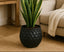 Black diamond-patterned metal pot with a snake plant on a beige rug in a living room.