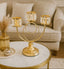 Gold candle holder on a marble table with a couch in the background