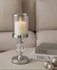 Decorative candle holder with a lit candle on a couch next to books.