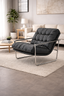 Black tufted vegan leather arm chair styled in a living room with chrome frame and plush cushioning.