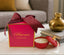 Red candle with decorative bow and 'Artemis' branding on a table.