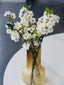 Graceful white artificial cherry blossoms displayed in a stylish vase for a timeless decorative touch.