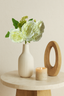 White artificial rose bunch, 31cm, styled in a white ribbed vase on a round table with a candle.