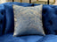 Atlantis Blue Designer Cushion styled on blue sofa, luxury accent pillow with gold wave pattern