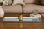 Decorative Mirrored Silver Tray on a coffee table with a vase, books, and a small ball in front of a beige sofa.