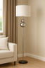 chrome floor lamp with white shade styled beside beige sofa in living room
