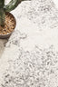 Close-up of Chrome Rita Silver Rug’s intricate texture and soft pile with plant décor.
