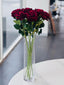 Clear cylinder vase with artificial red roses, stylish floral arrangement.