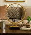 Decorative piece with a gold frame and black tree-like design on a table in a living room setting.
