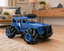 A blue and black RC crawler truck with oversized rugged tires, shown in a modern living room setting on a wooden floor.