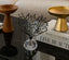 Decorative black crystal tree sculpture on a clear base with books and decorative bowls in the background.