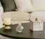 Decorative items including a candle, glass vase with decorative crystal gold table decor, and mirrored box on a table.