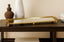 Gold Mirror tray on a wooden table with decorative items against a beige wall