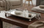 Decorative Silver Mirror Tray with a diffuser and coasters on a wooden table in a living room setting.