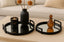 Decorative black mirrored metal tray including a black vase, candle, and mirrors on a coffee table.