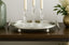 Decorative oval mirrored tray with glass candle holders and candles on a wooden surface.