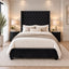 A black upholstered bed with a tall tufted headboard and matching footboard, styled in a bright bedroom with cream bedding, beige pillows, nightstands, lamps, and a large rug.